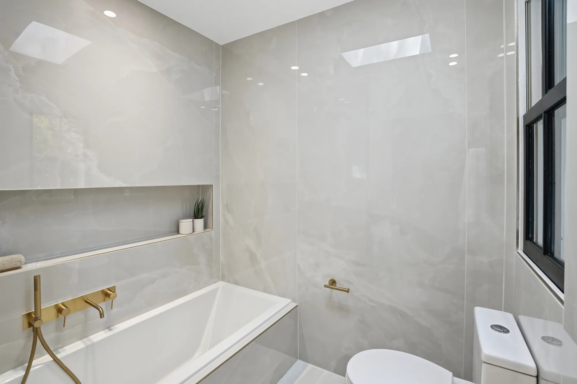 Porcelain-slab bath with soaking tub and brushed gold fixtures at Casa Ulivo