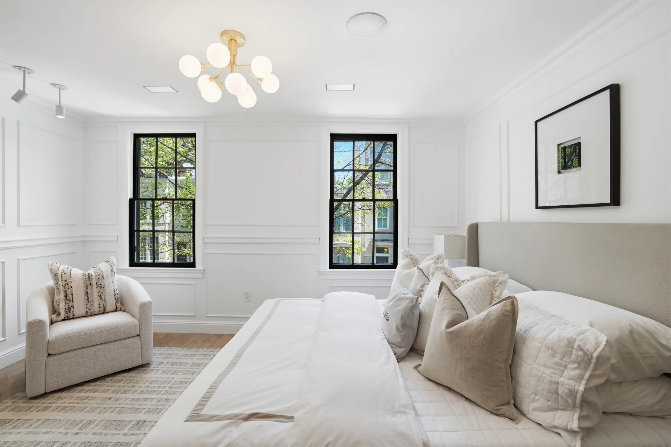 Primary bedroom with paneled walls and brass chandelier at Casa Ulivo