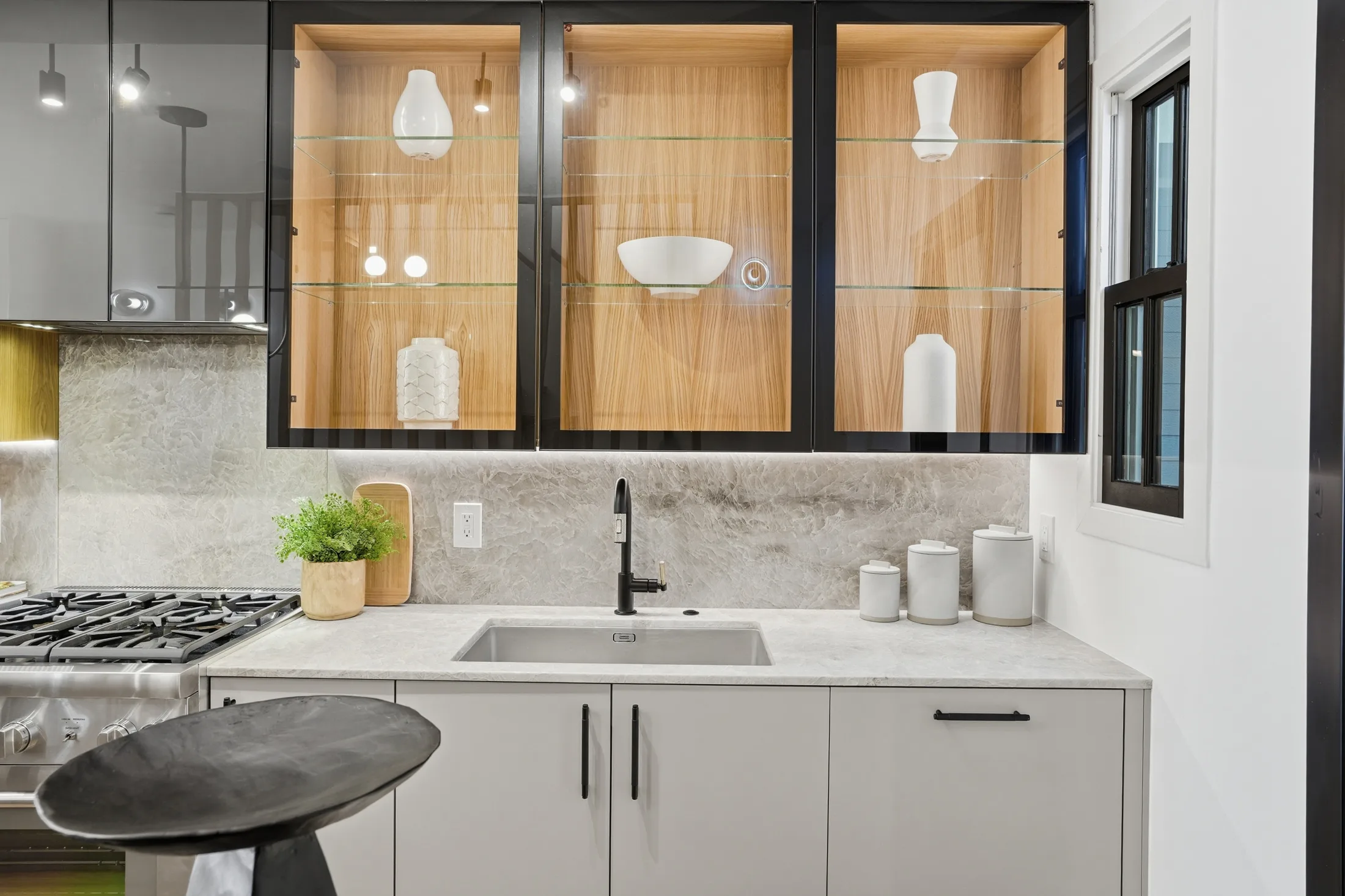 Illuminated timber and smoked glass cabinets above the range at Casa Ulivo